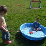 Jordan loves to climb in the empty pool and play in there.  Here is Anna trying to teach him to bang on it with a stick like a drum.